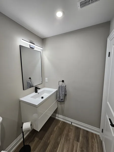 Basement bathroom Toronto: the floating vanity and its lit mirror — built in East Gwillimbury