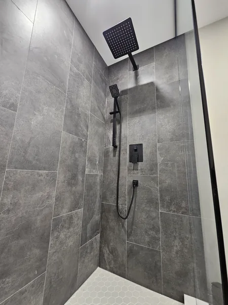 Basement bathroom Toronto: the tiled shower with matte black fixtures — built in East Gwillimbury