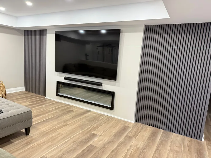 Finished basement Toronto: the TV and electric fireplace wall between two slat panels — built in East Gwillimbury